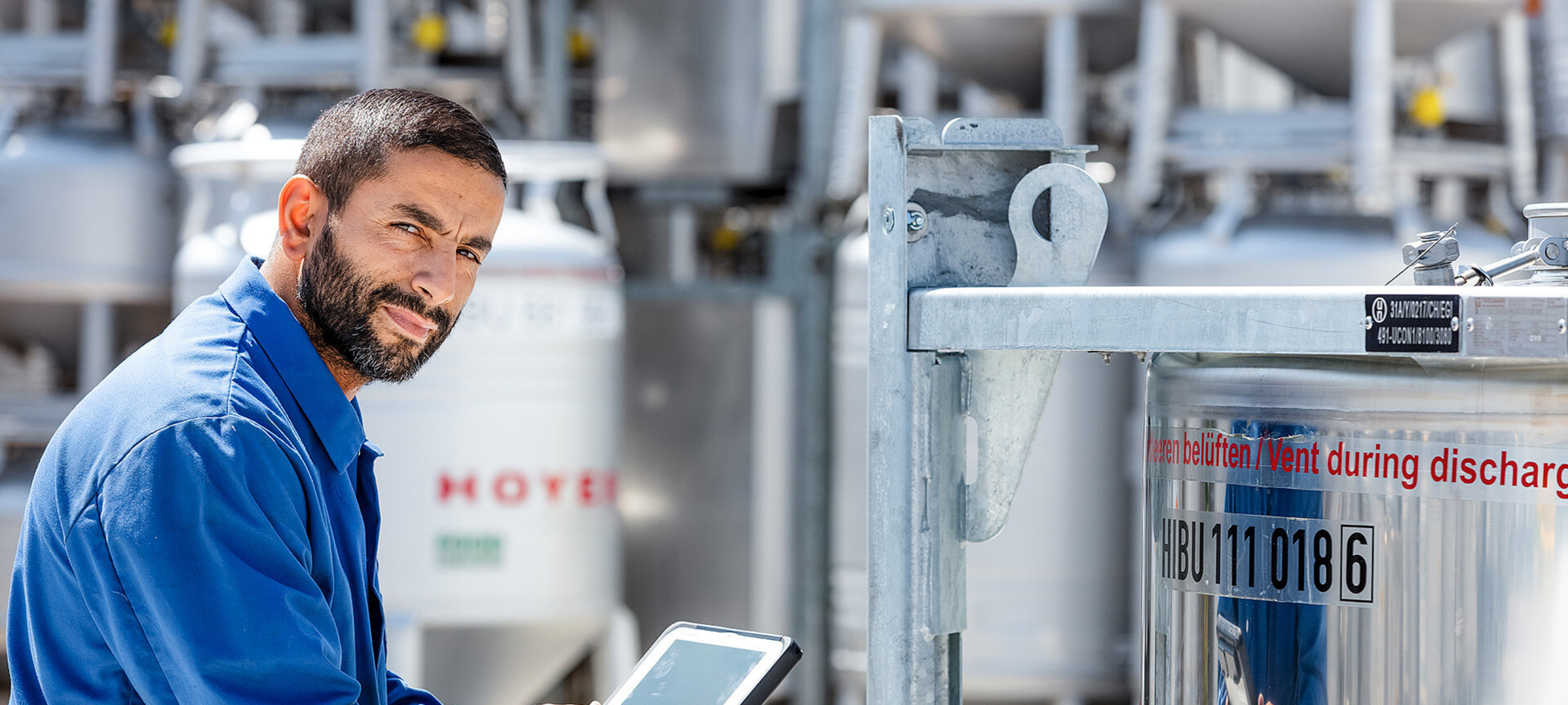 Mitarbeiter mit Tablet kniet vor IBC